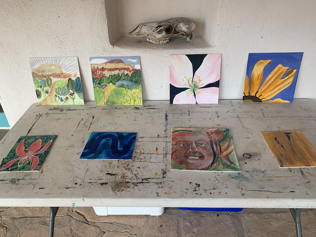 8 paintings, displayed on a table under a cow skull